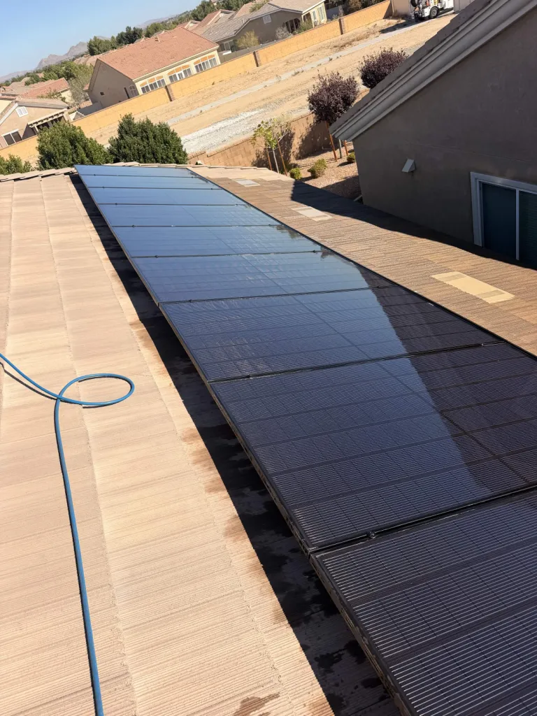 A long row of cleaned solar panels on a tiled residential roof.
