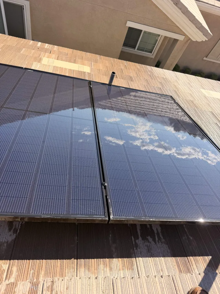 Close view of cleaned rooftop solar panels reflecting the sky and nearby roof.