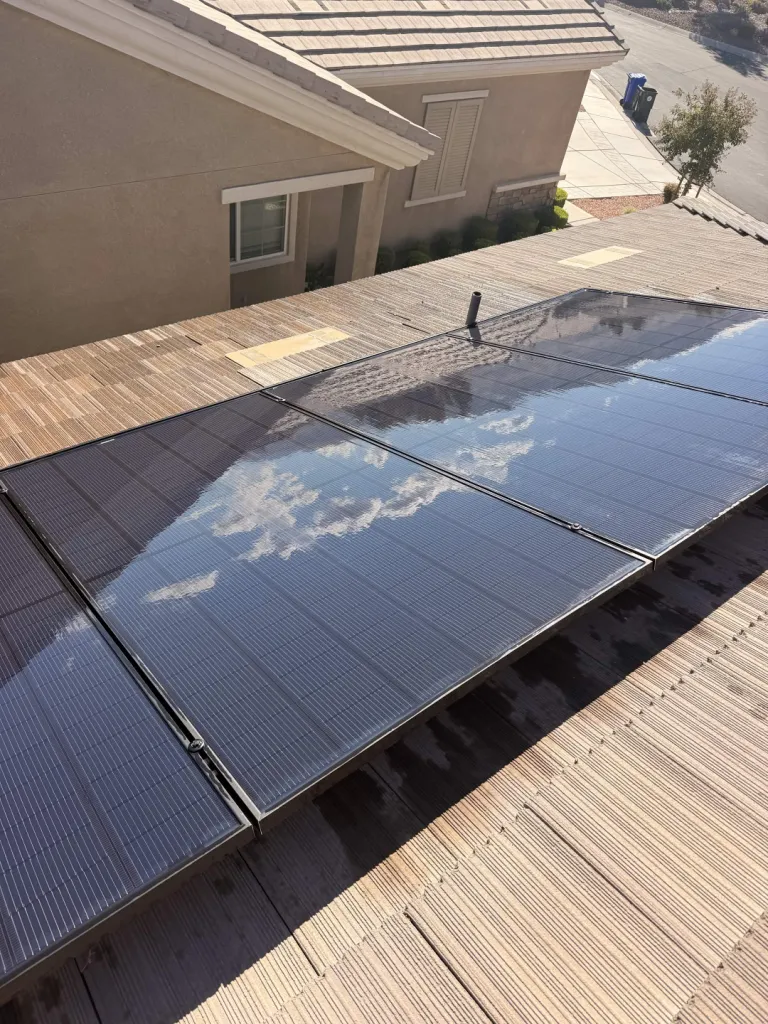 Cleaned solar panels reflecting clouds beside a neighboring home.